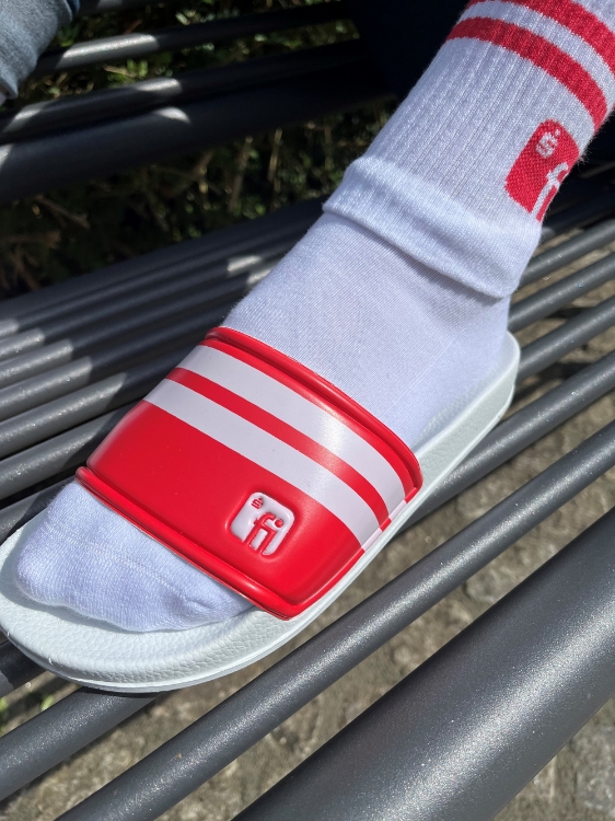 Badelatsche mit Fuß in weißer Socke, weiße Sohle, Brücke in weiß/rot gestreift mit Finanz Informatik Logo