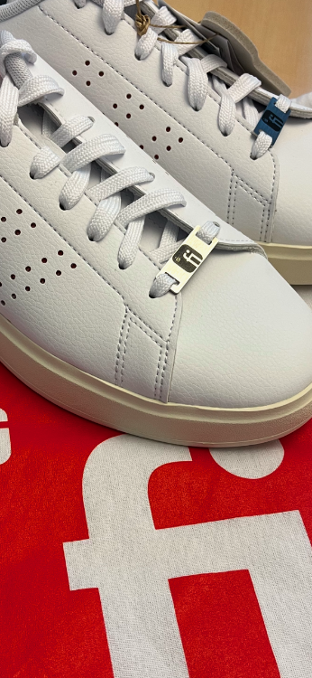 Weißer Sneaker mit Metall Plättchen im Schnürsenkel mit Finanz Informatik Logo