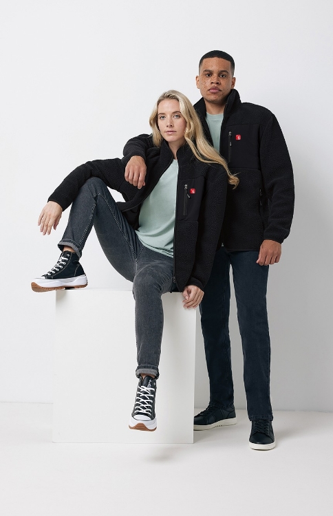 Männliches und weibliches Model tragen eine schwarze Teddy Fleecejacke mit rotem Finanz Informatik Logo auf der linken Brust